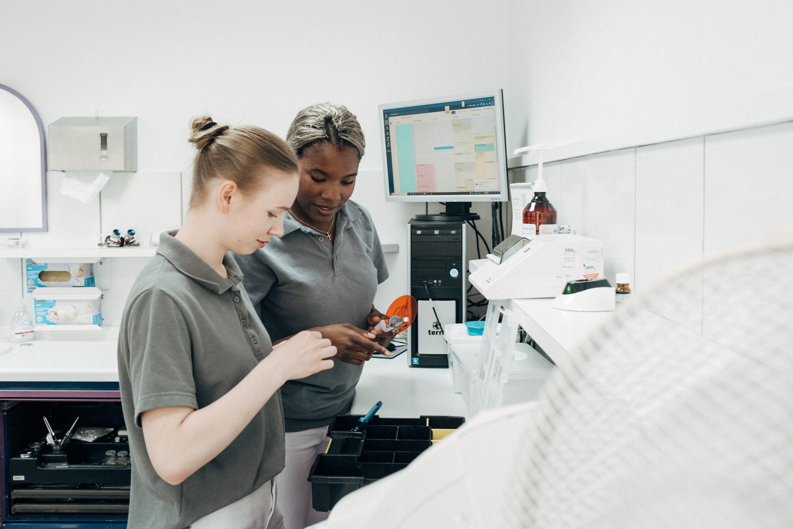 Zwei Mitarbeiterinnen bereiten ein Behandlungszimmer für eine Zahnbehandlung vor