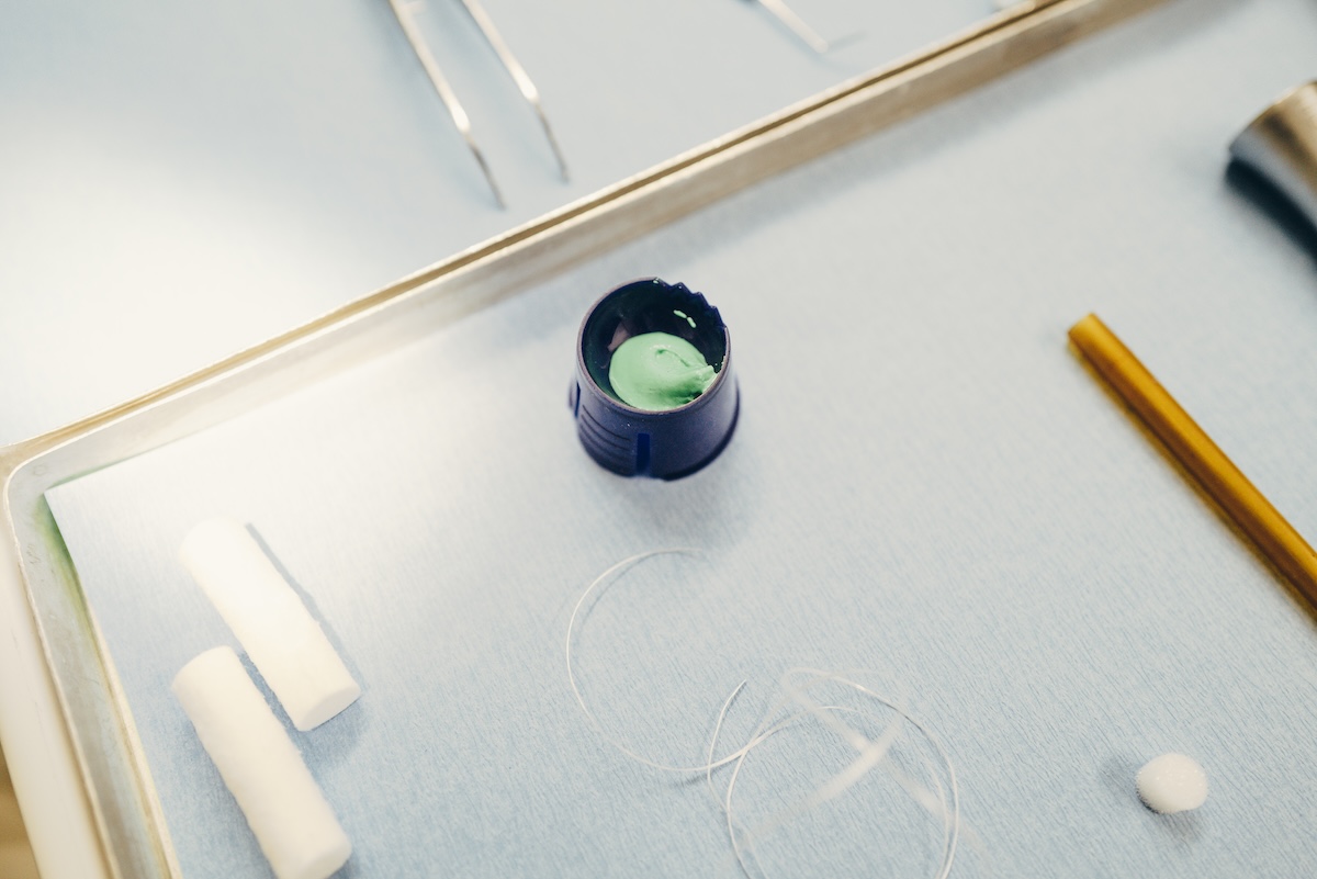 Nahaufnahme eines für die Prophylaxe vorbereiteten Trays mit Zahnseide, Watte und einem Gel